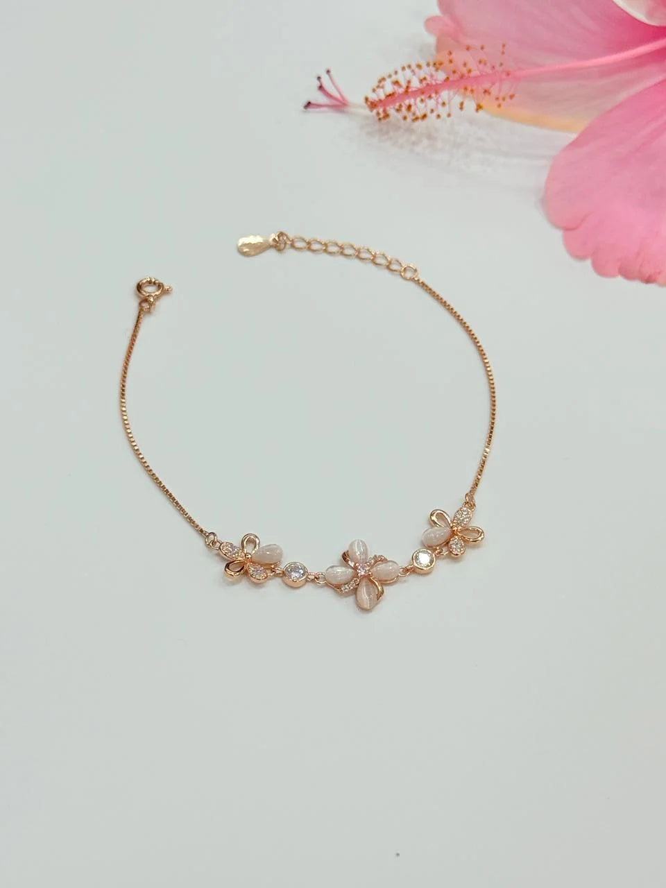 Rose gold bracelet with floral designs on a light background