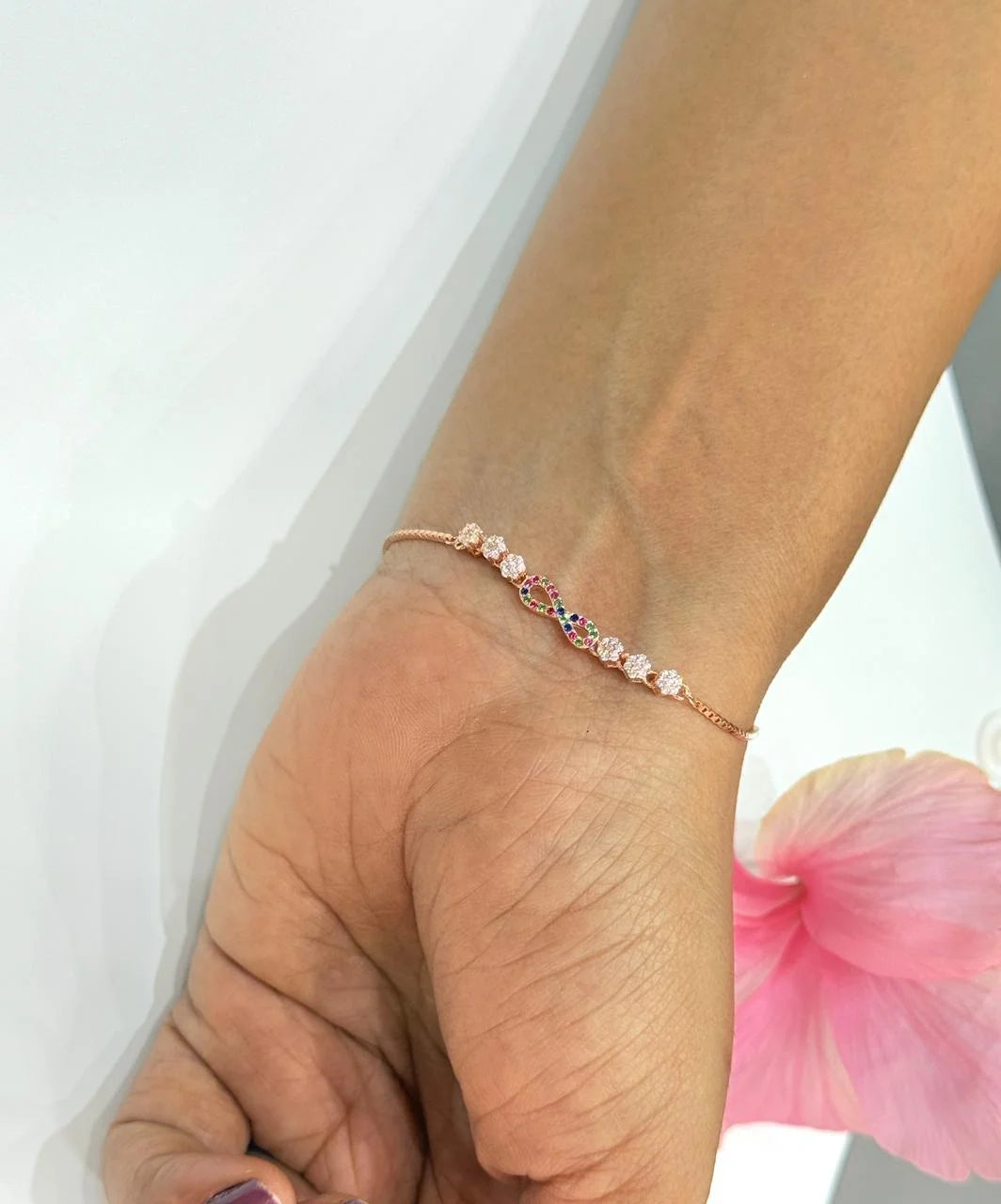 Hand wearing a delicate bracelet with pink beads on a white background