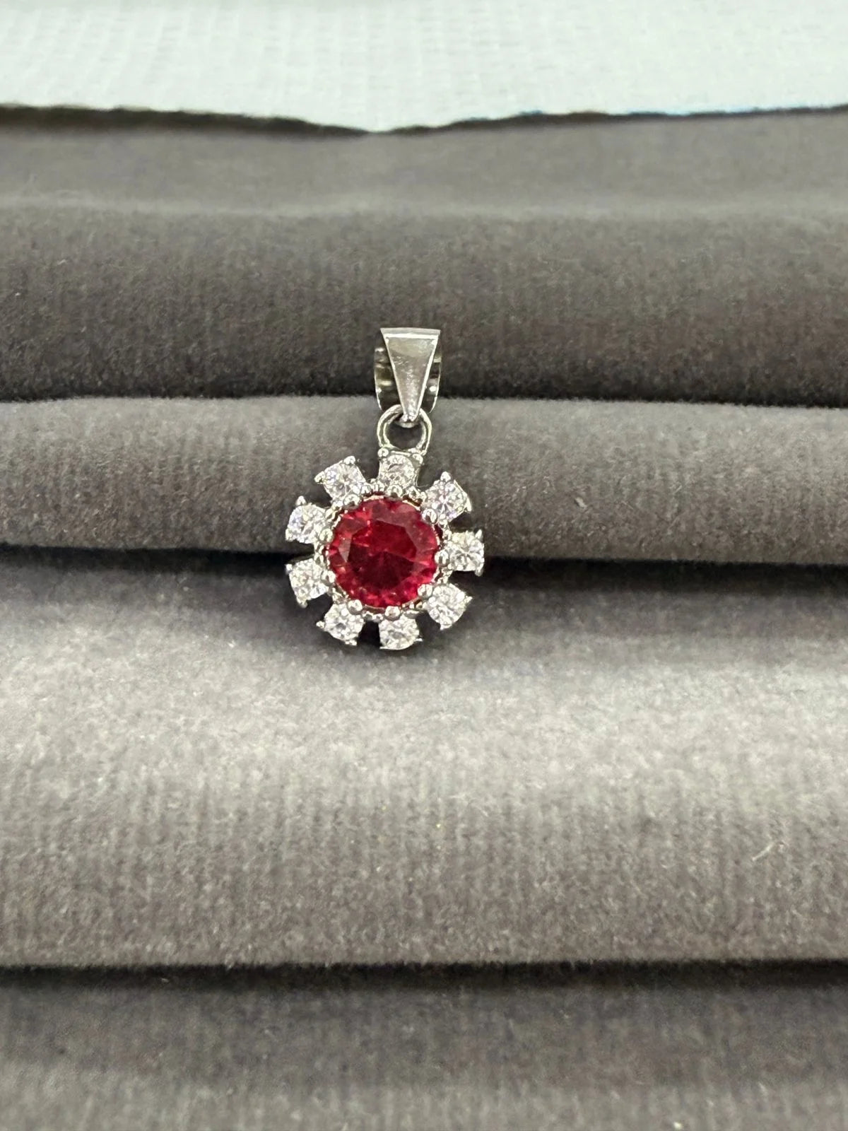 Silver pendant with a red gemstone on a gray surface