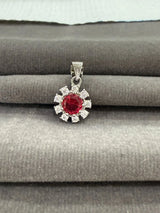 Silver pendant with a red gemstone on a gray surface