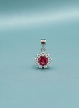 Silver pendant with a red gemstone on a light blue background