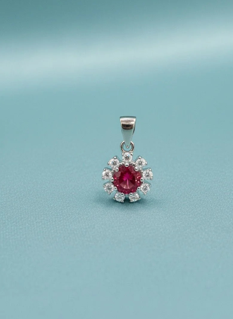 Silver pendant with a red gemstone on a light blue background