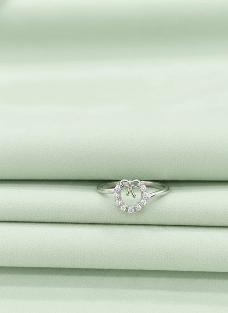 Silver ring with small diamond-like stones on a light green fabric background