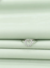 Silver ring with small diamond-like stones on a light green fabric background