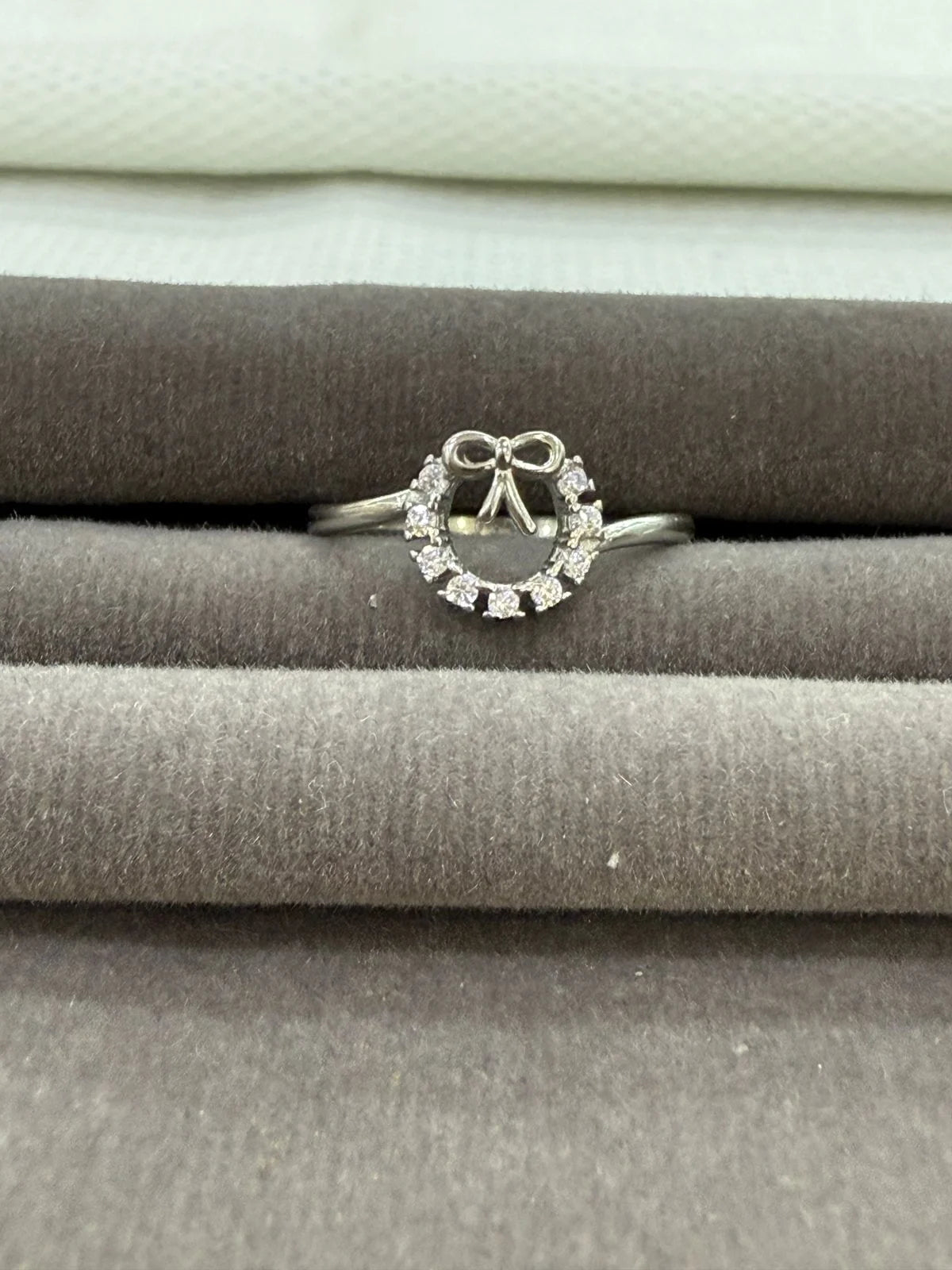 Silver ring with diamond accents on a gray surface