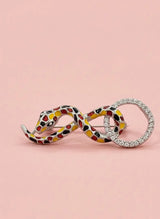 Pendants on a pink background, one snake-shaped with a colorful pattern and the other silver.