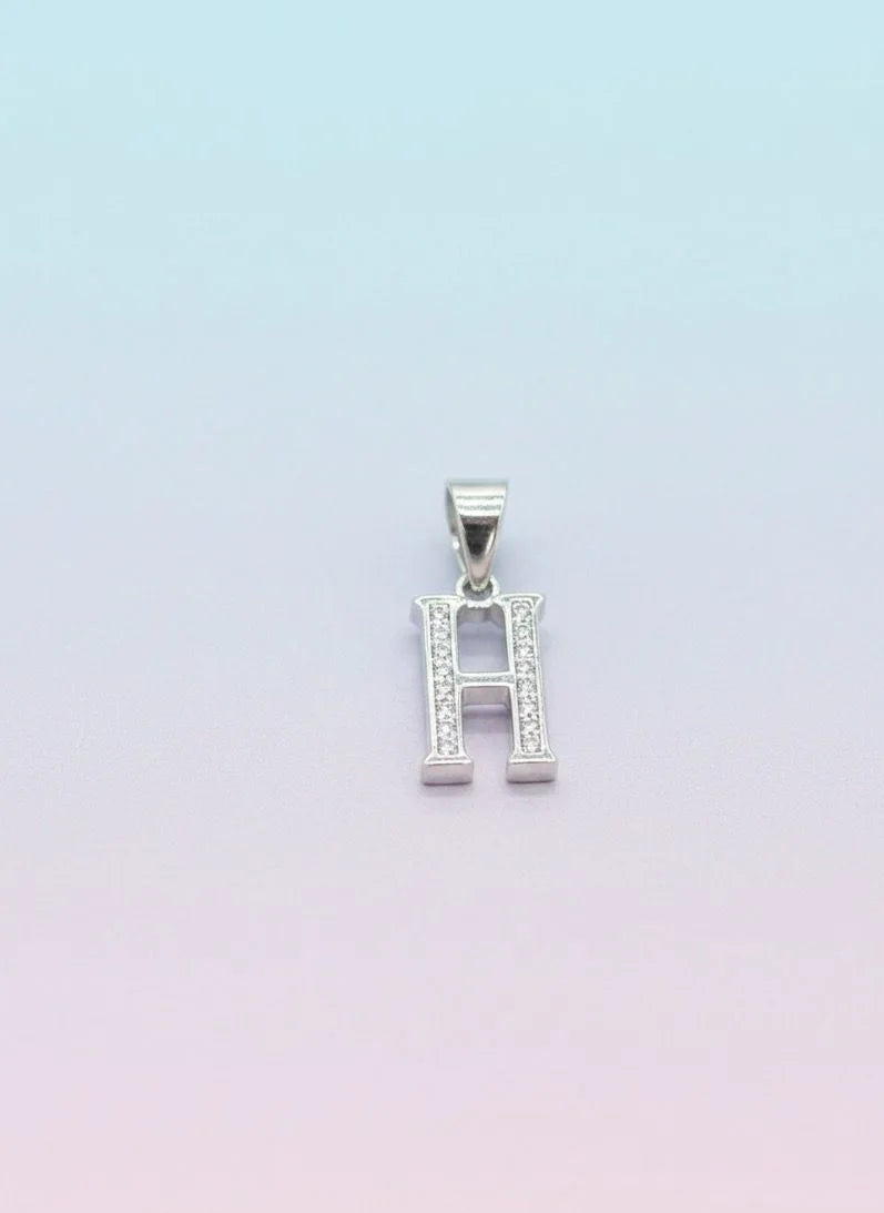 Silver pendant with letter 'H' on a light gradient background
