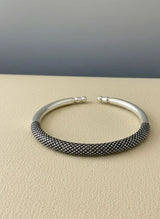 Silver bracelet with textured band on a beige surface