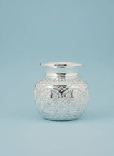 Decorative glass jar with silver lid on a light blue background
