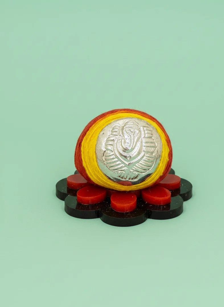 Decorative item with a central silver emblem, surrounded by red and black elements on a light green background