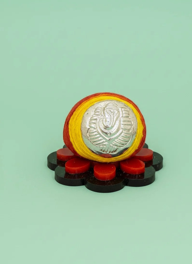Decorative item with a central silver emblem, surrounded by red and black elements on a light green background
