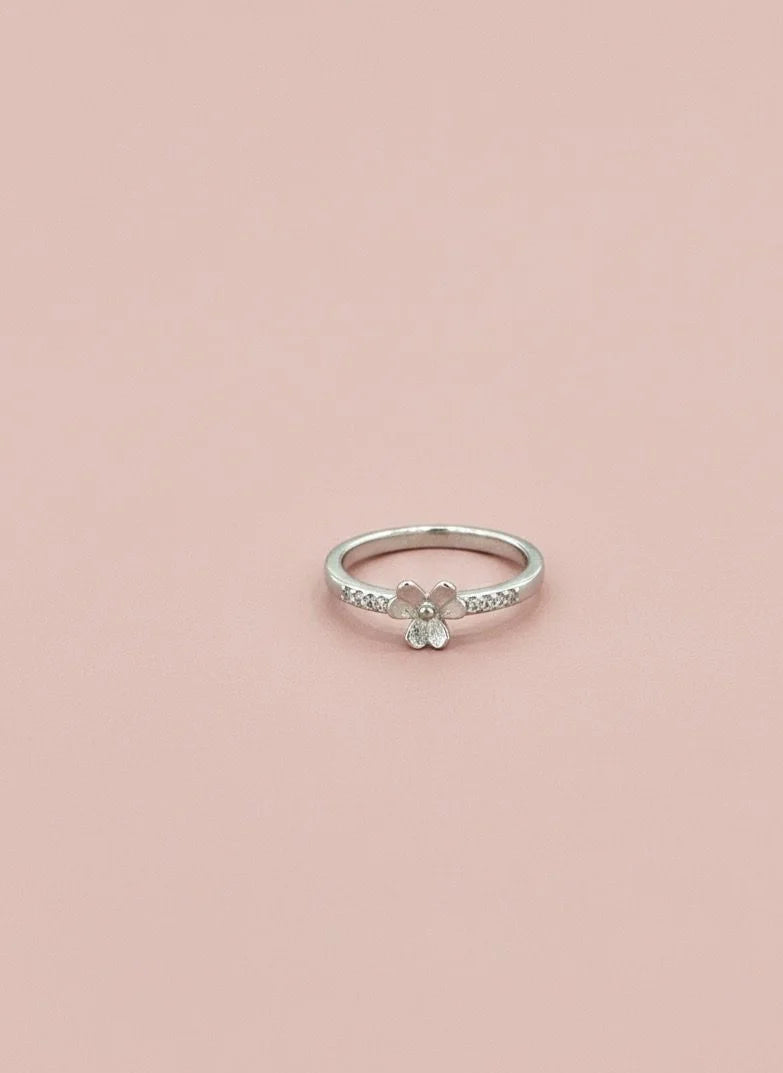 Silver ring with a floral design on a pink background