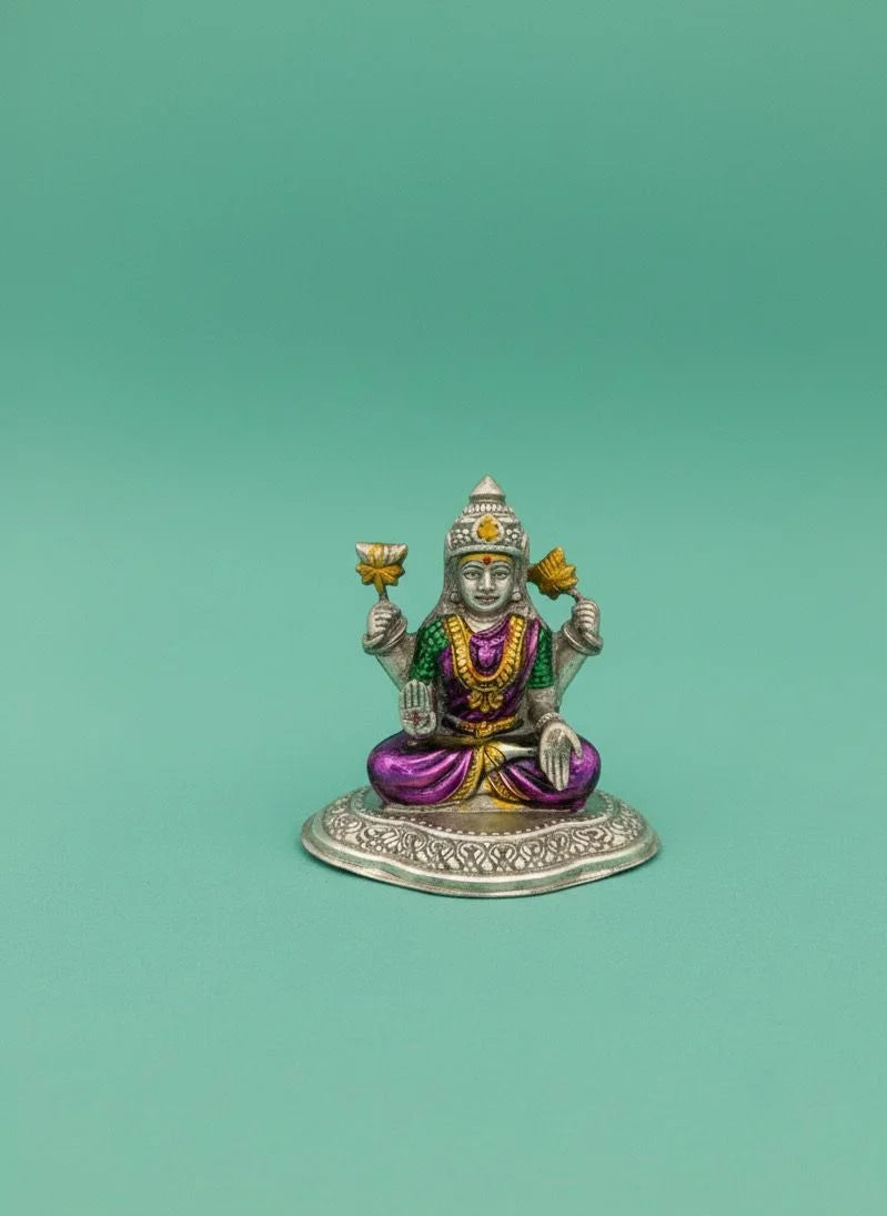 Small figurine of a deity with colorful attire on a green background