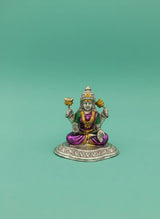 Small figurine of a deity with colorful attire on a green background