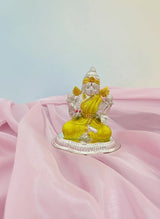 Decorative statue of a seated figure with yellow garment on pink fabric