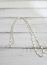 Silver chain necklace on a white wooden surface