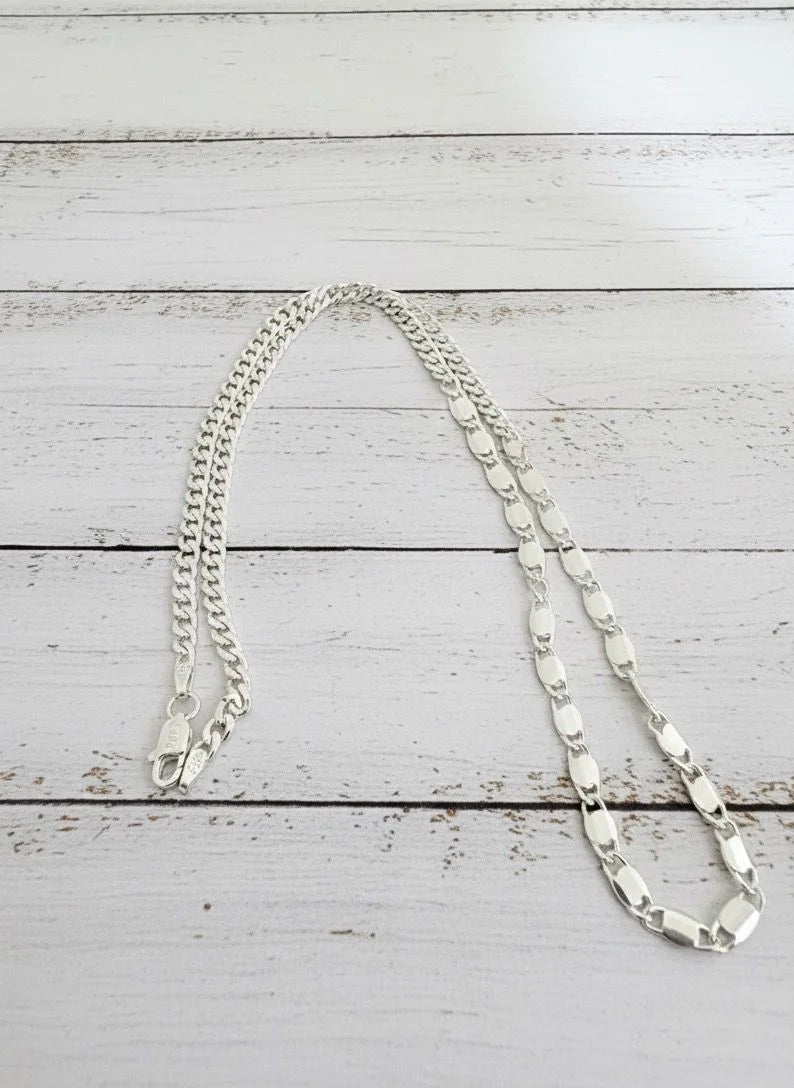 Silver chain necklace on a white wooden surface