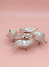 Silver leaf-shaped object on a pink background