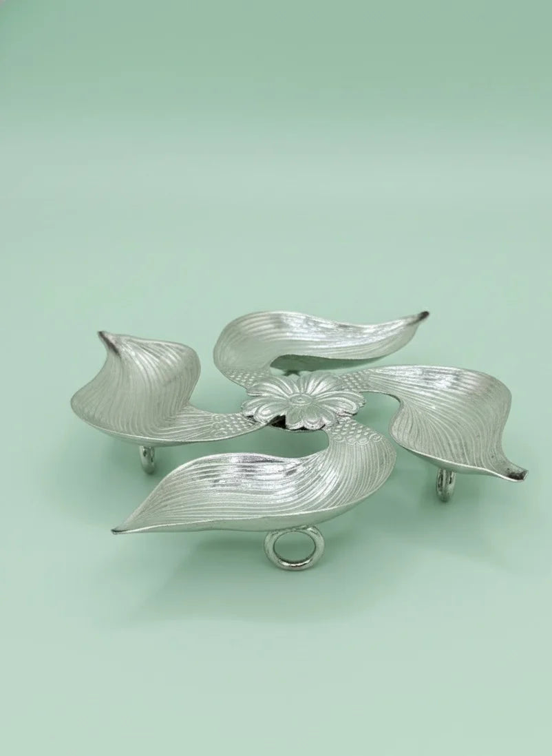 Silver leaf-shaped caddy on a light green background