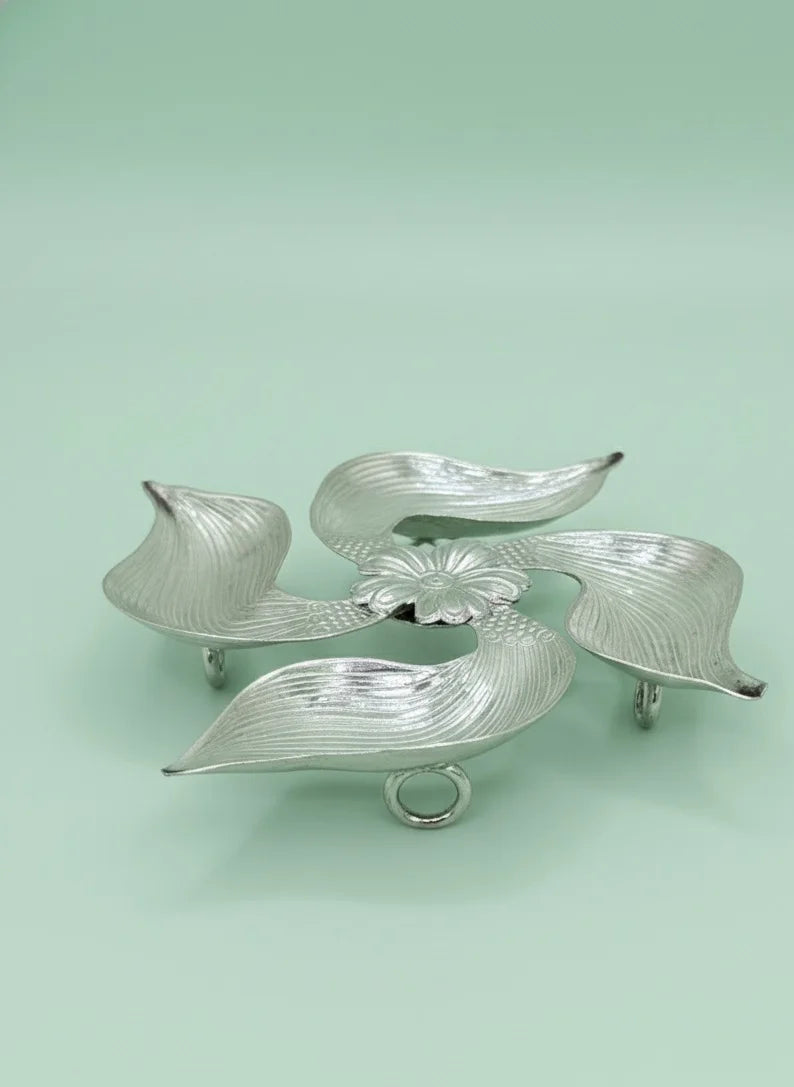Silver leaf-shaped caddy on a light green background