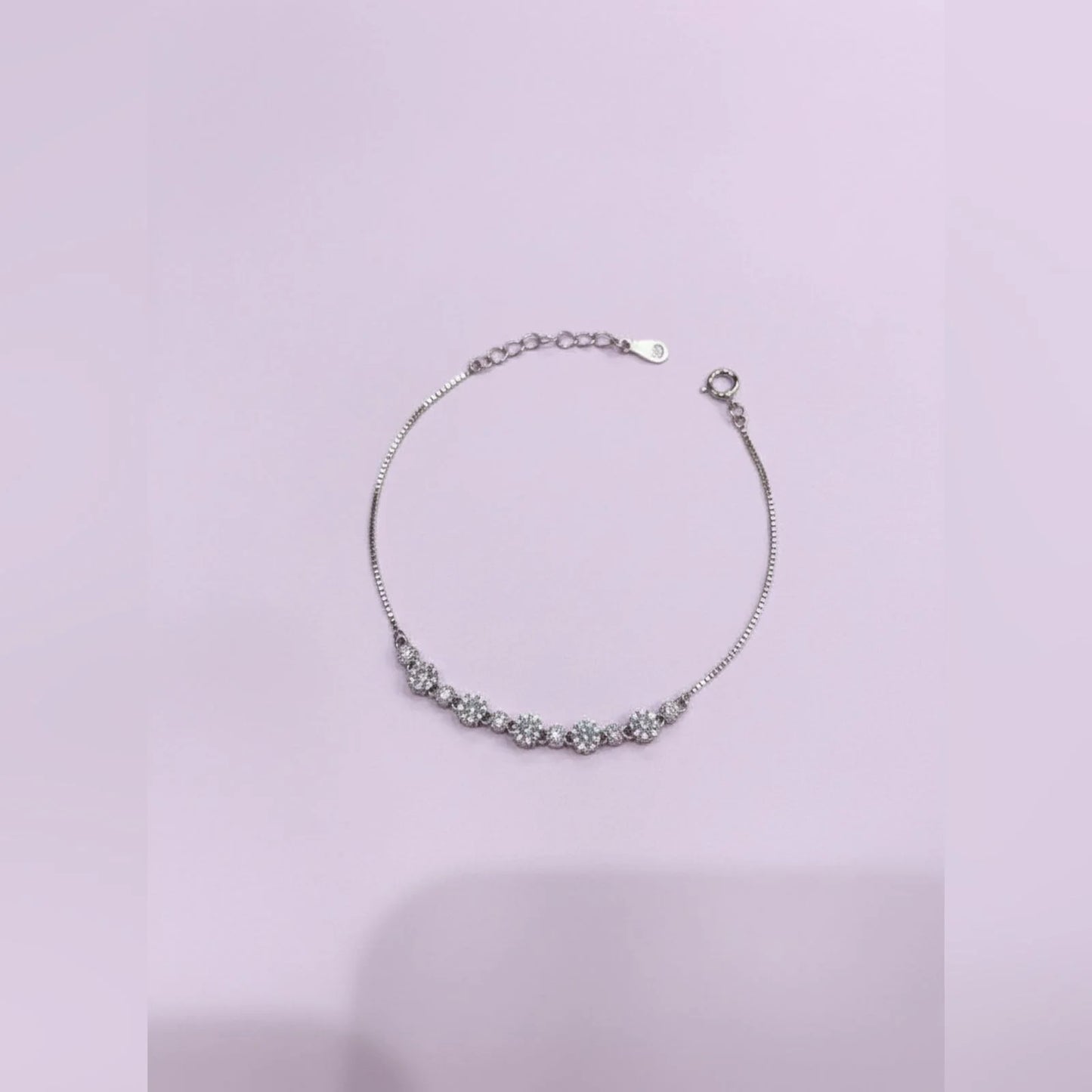 Silver bracelet with floral design on a light purple background