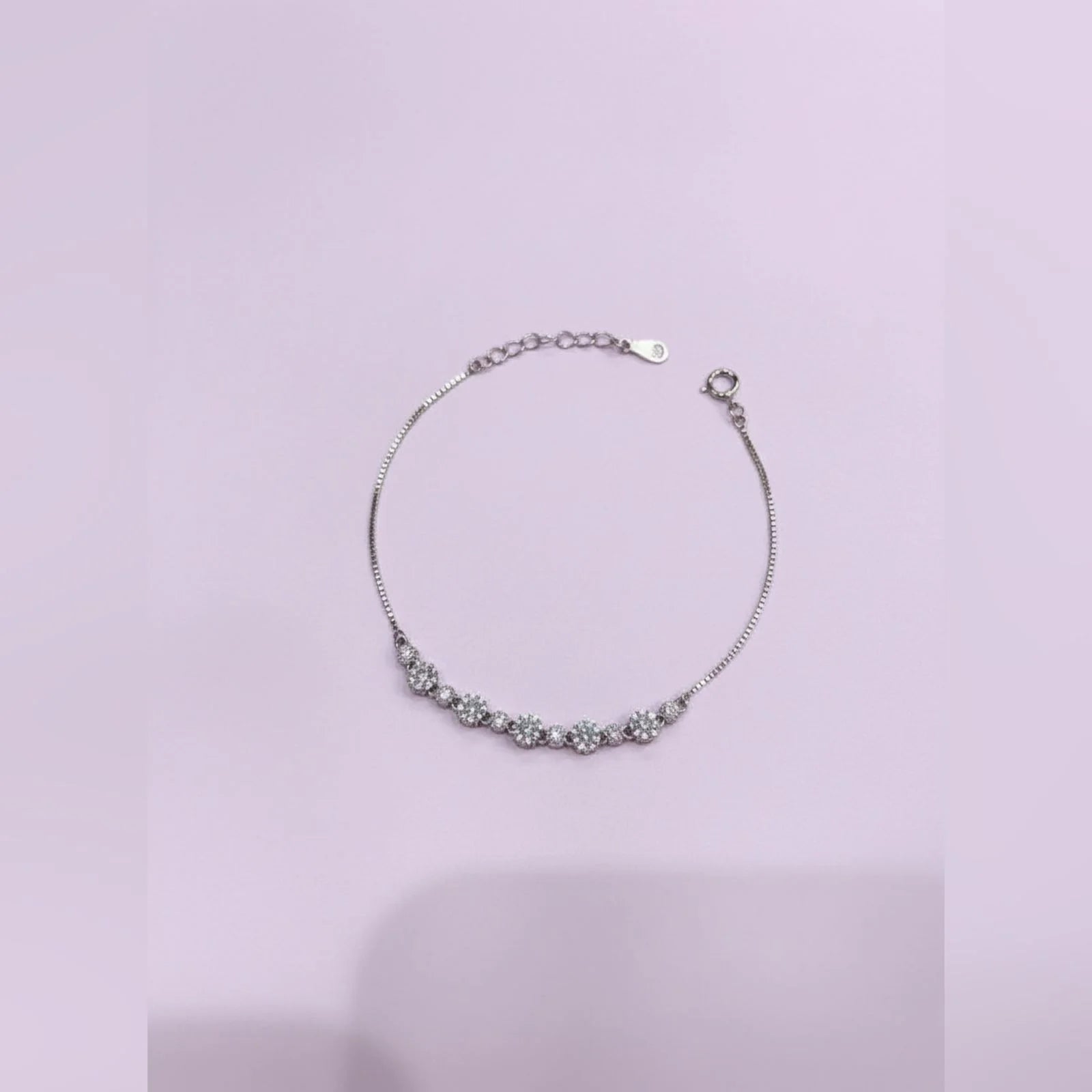 Silver bracelet with floral design on a light purple background