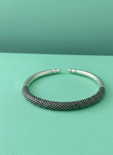 Silver textured bangle on a teal background