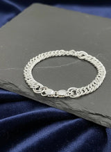 Silver bracelet on a dark slate surface with a blue satin background