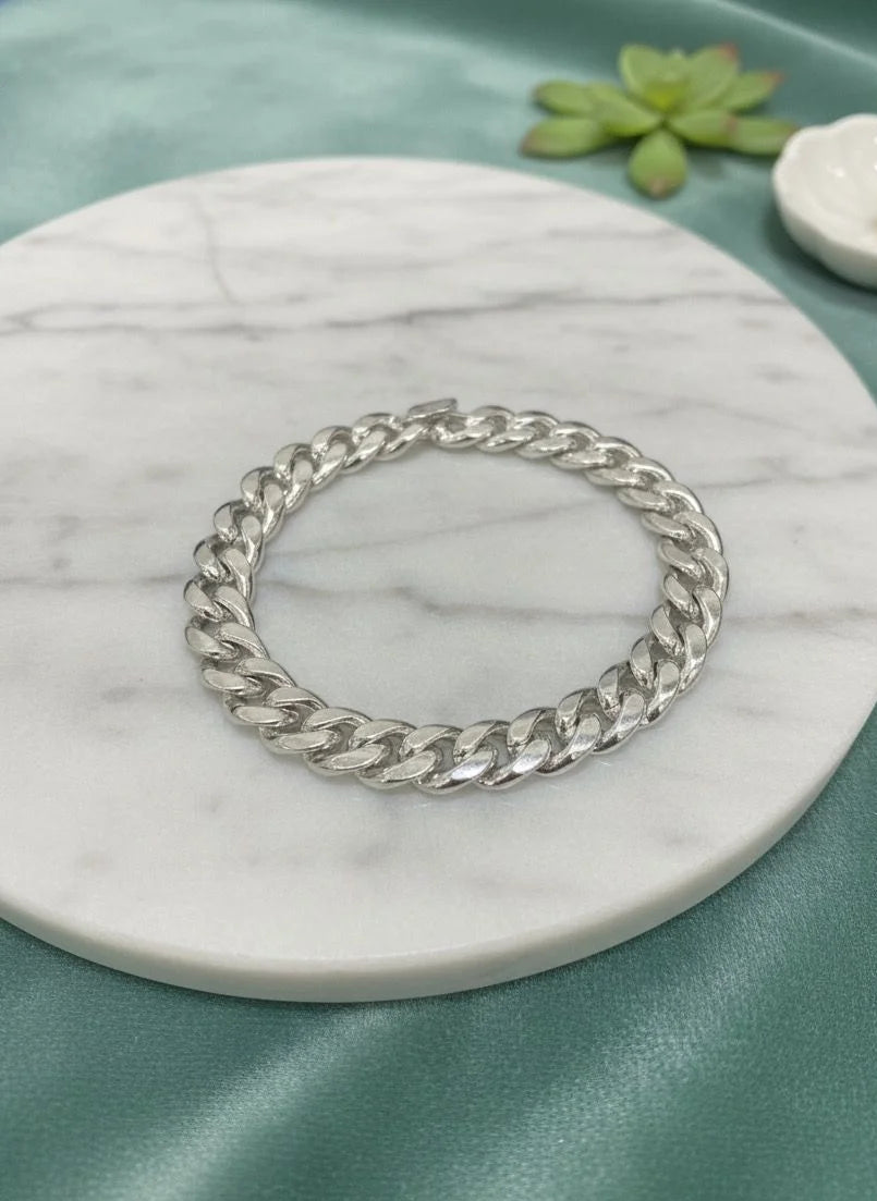 Silver chain bracelet on a marble coaster with a green background