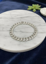Silver chain bracelet on a marble coaster with a blue fabric background