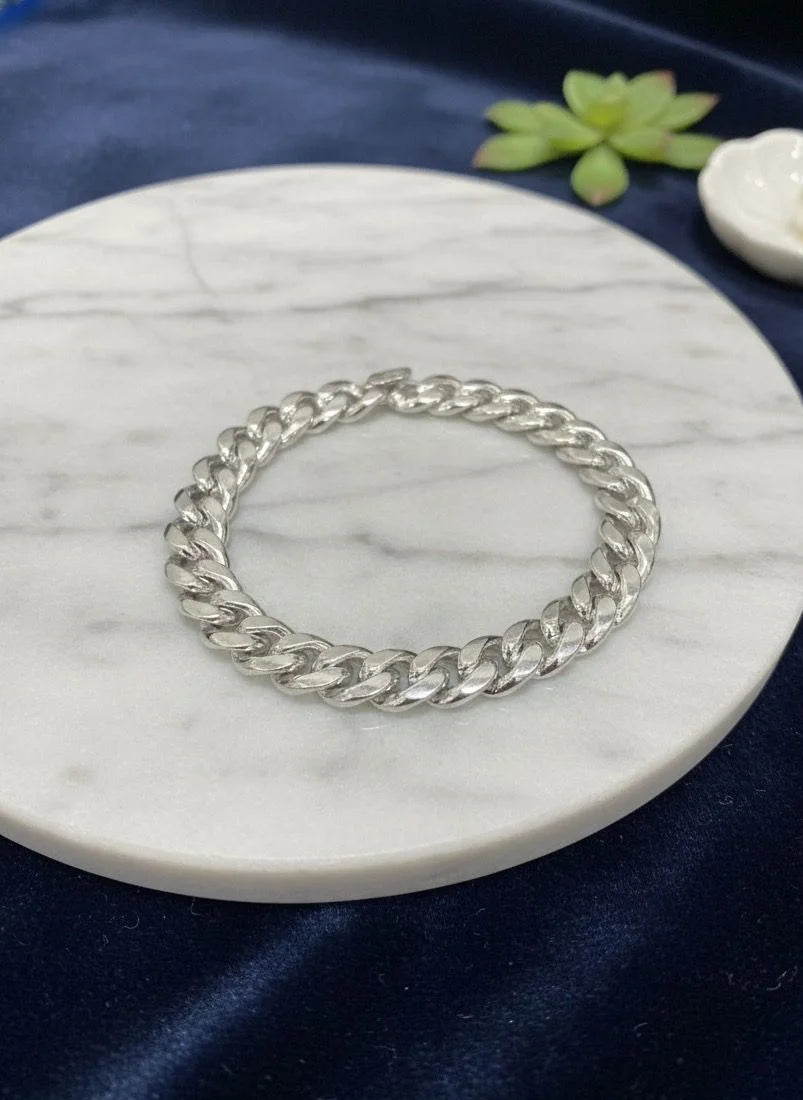 Silver chain bracelet on a marble coaster with a blue fabric background