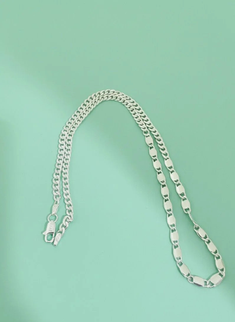 Silver chain necklace on a light green background