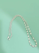 Silver chain necklace on a light green background