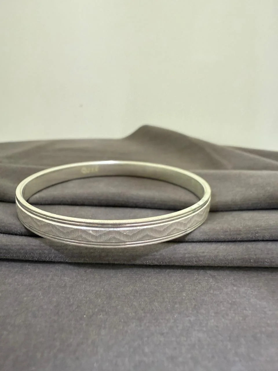 Silver bracelet on a gray fabric background