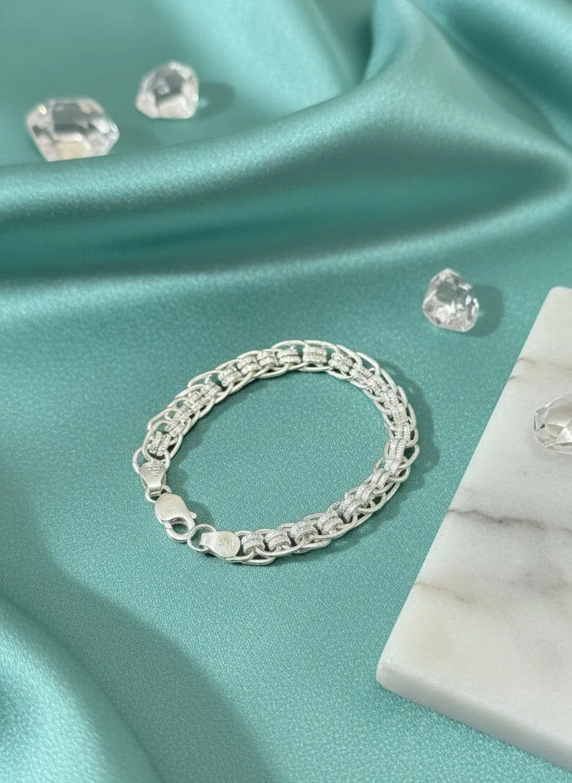 Silver bracelet on a teal fabric background with diamonds.