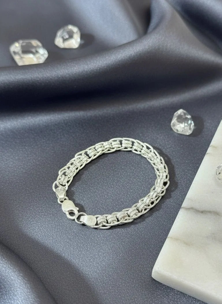 Silver bracelet on a gray fabric background with clear gemstones.