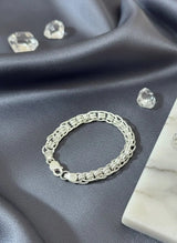Silver bracelet on a gray fabric background with clear gemstones.
