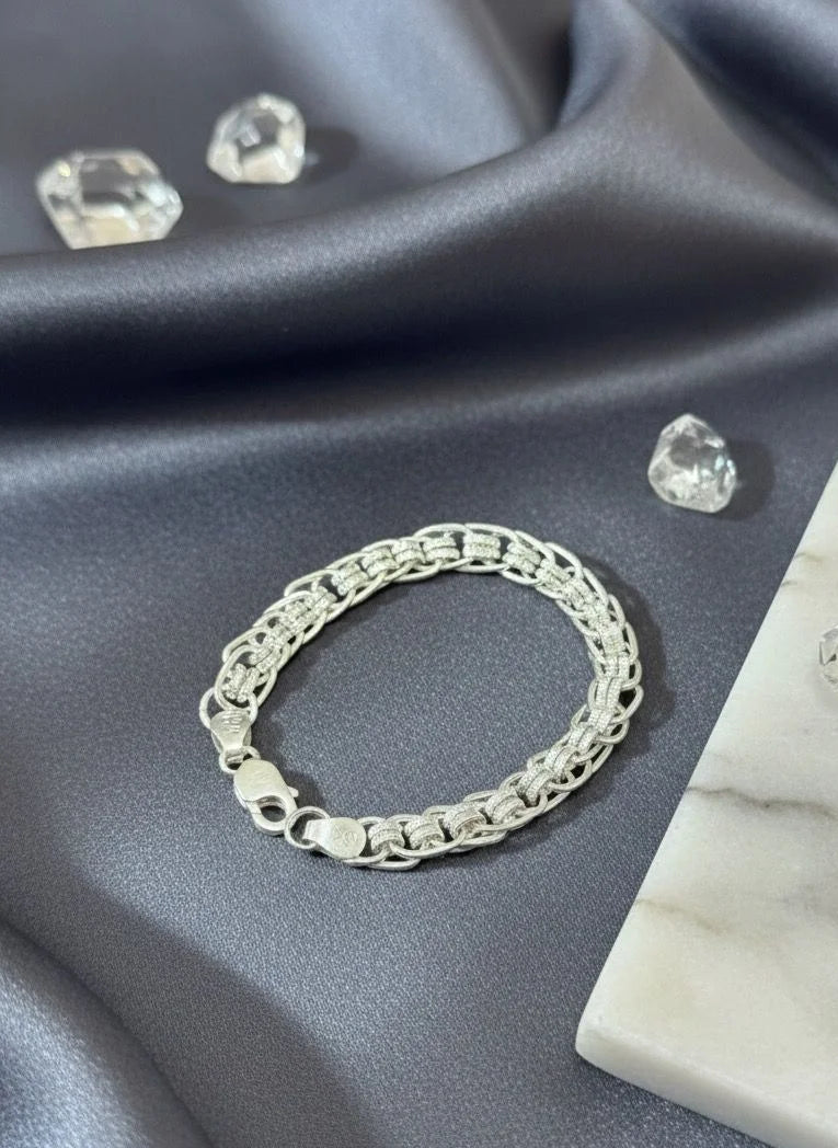Silver bracelet on a gray fabric background with clear gemstones.