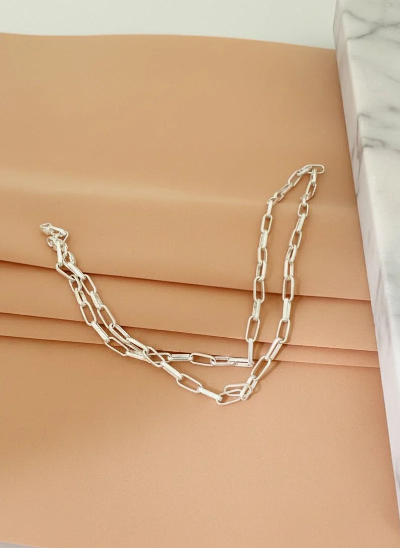 Silver chain necklace on a beige surface