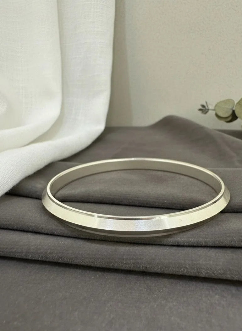 Gold bracelet on a gray surface with a neutral background
