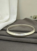 Gold bracelet on a gray surface with a neutral background