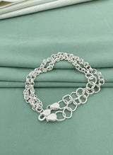 Silver chain bracelet on a teal fabric background