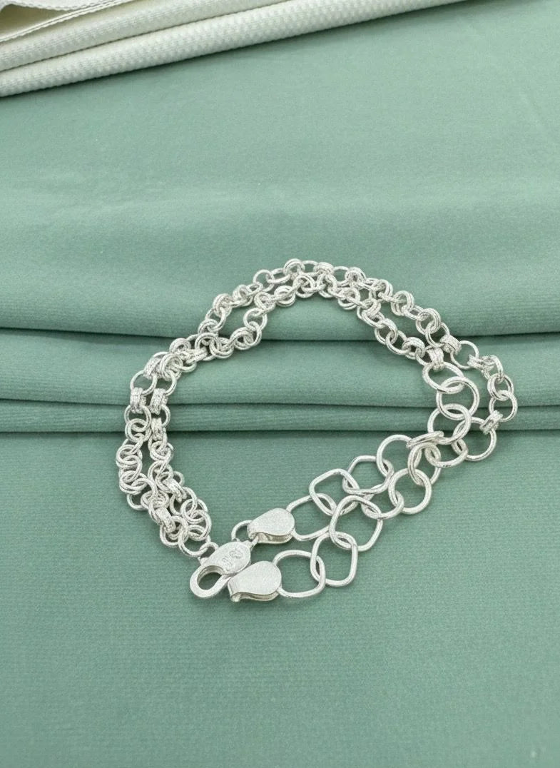 Silver chain bracelet on a teal fabric background
