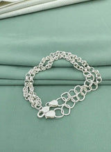 Silver chain bracelet on a teal fabric background