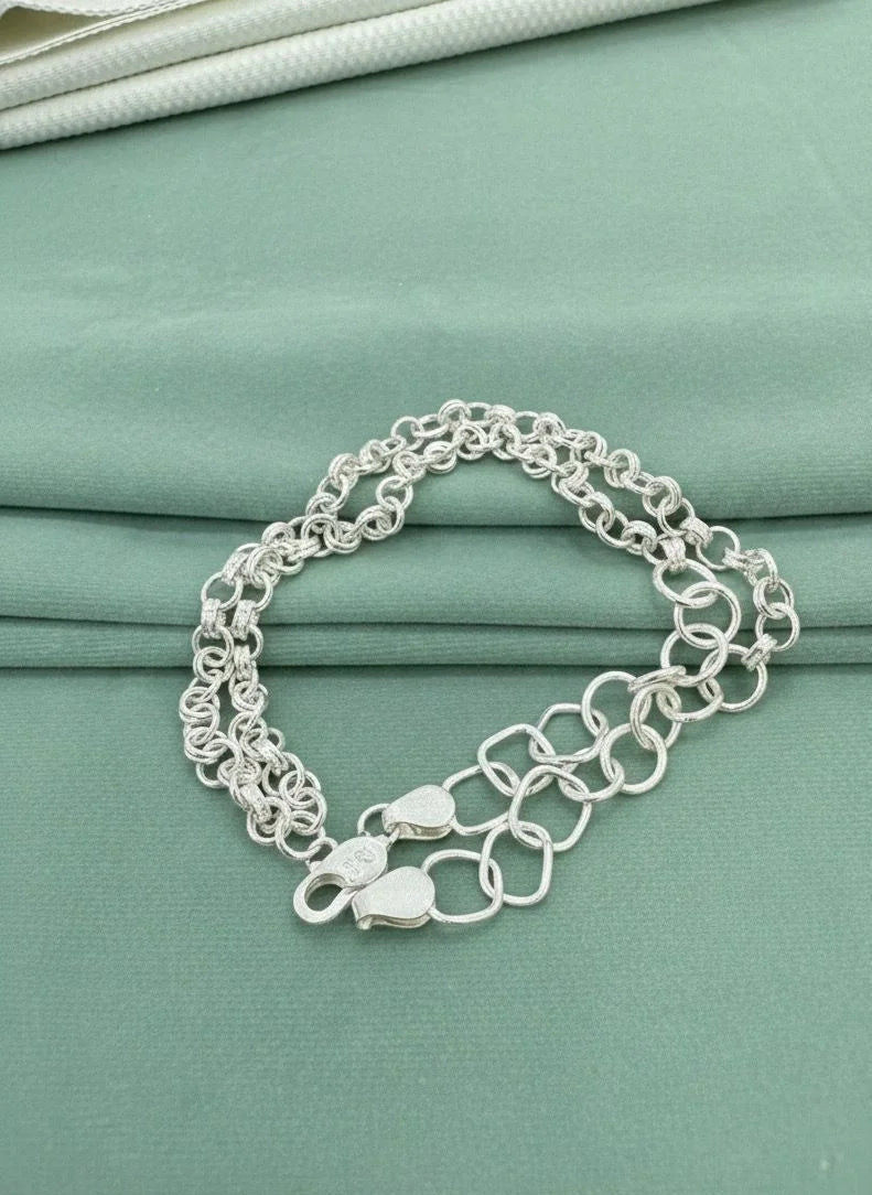 Silver chain bracelet on a teal fabric background