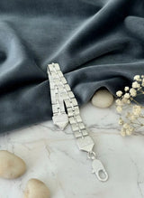Silver bracelet on a marble surface with stones and small flowers
