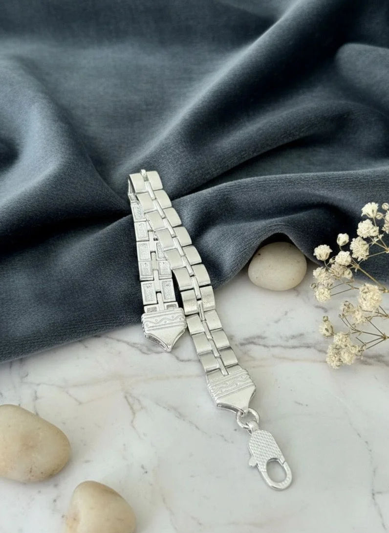 Silver bracelet on a marble surface with stones and small flowers