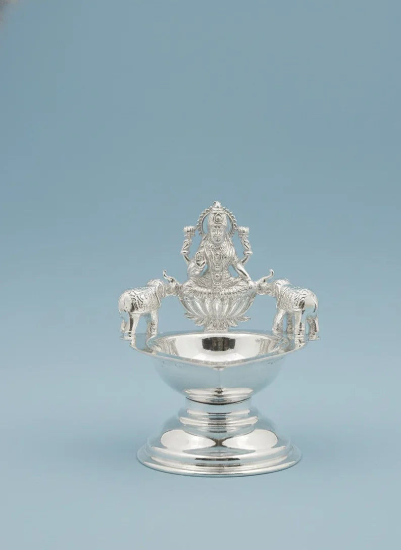 Silver decorative item with intricate design on a light blue background