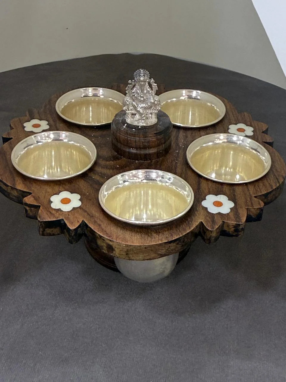 Wooden platter with silver bowls and a crystal figure on a gray surface