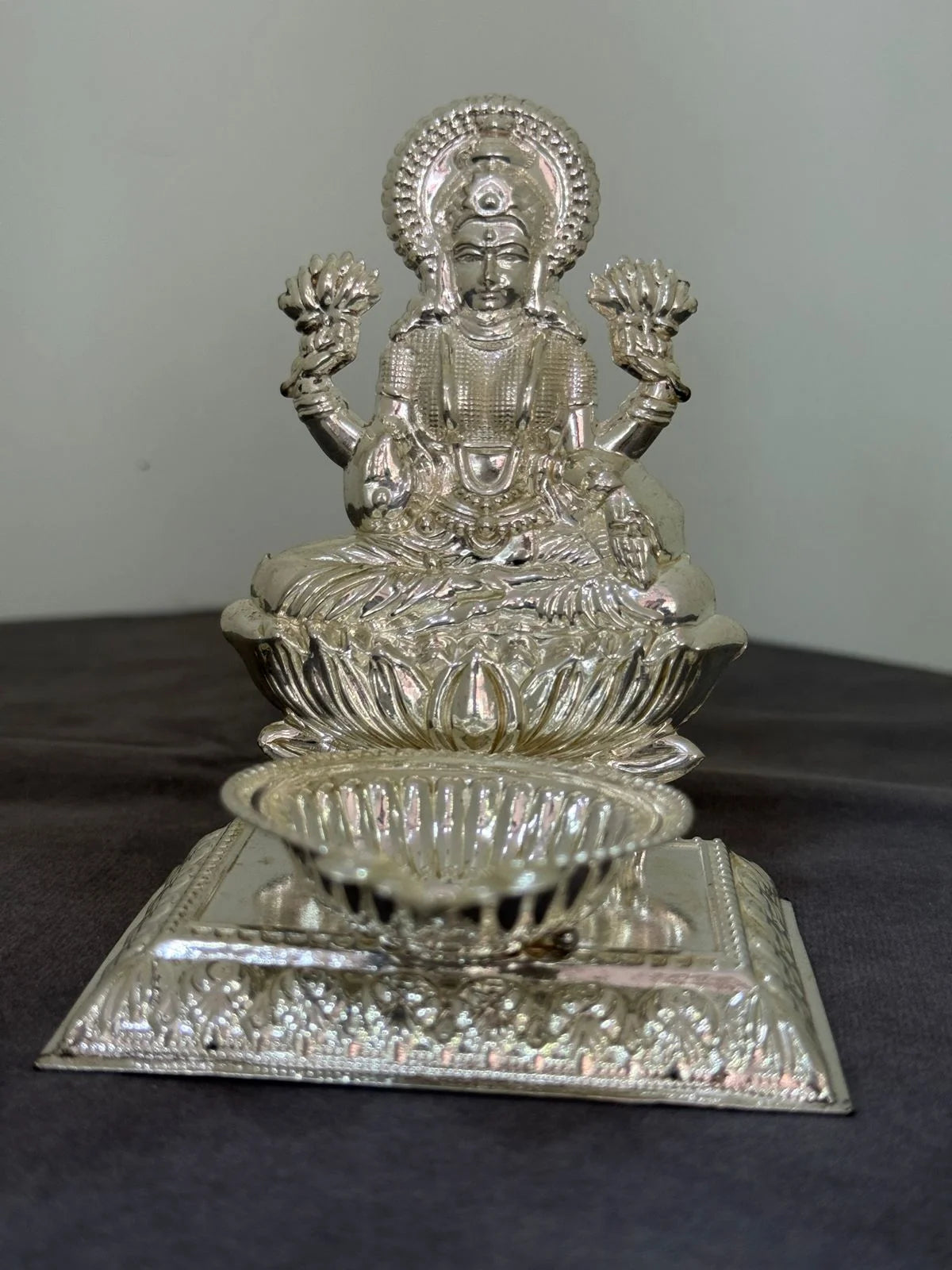 Silver lakshmi on a dark surface with a gray background